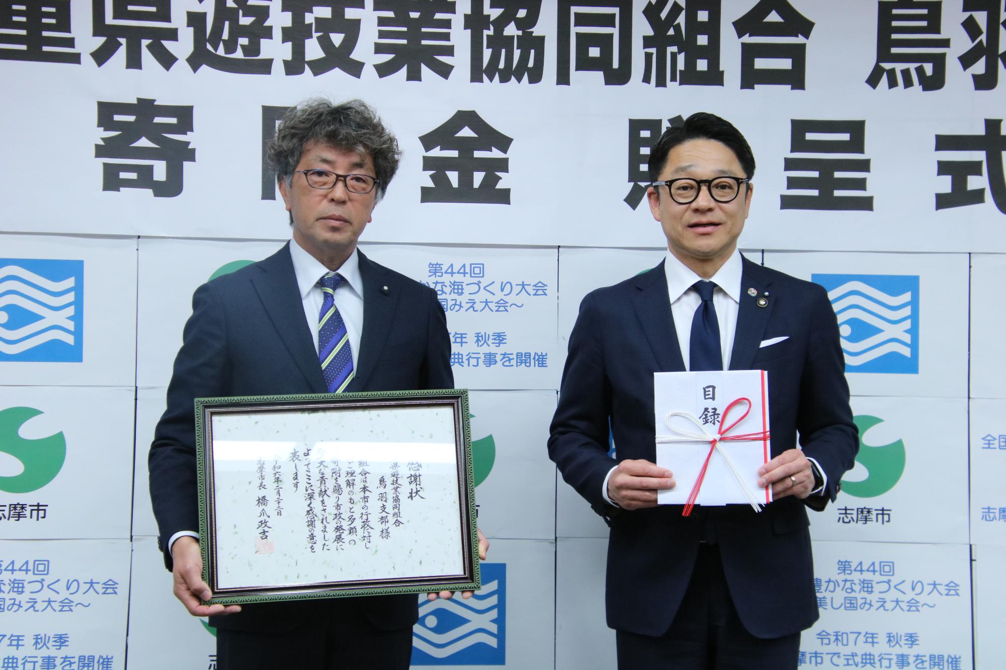 寄附金贈呈式で写真撮影をする橋爪市長と三重県遊技業協同組合鳥羽支部の山口支部長